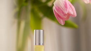 Olio cosmetico in flacone di vetro accanto a fiori freschi