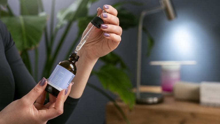 Siero cosmetico con contagocce accanto a una pianta
